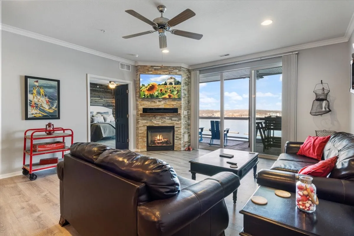 A comfortable living room with a fireplace, large windows, and artwork on the wall. The space is set for relaxation and socializing, featuring scenic views and an inviting atmosphere perfect for unwinding in privacy and security.