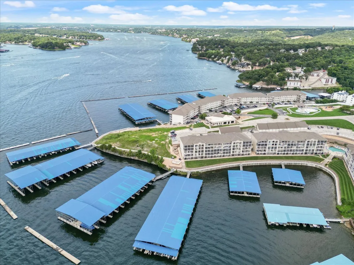 A sweeping view of the lake’s waterfront, with marinas, residential buildings, and green spaces visible along the shore. The scene showcases the broader lakeside environment, hinting at local adventures like boating or exploring nearby attractions just minutes away.