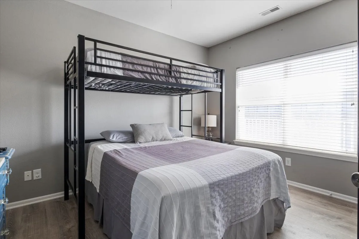A bright and cheerful bedroom featuring a lofted bed above a lower bed, with ample natural light pouring in through a nearby window. The arrangement is ideal for children or multi-generational stays requiring flexible sleeping solutions.