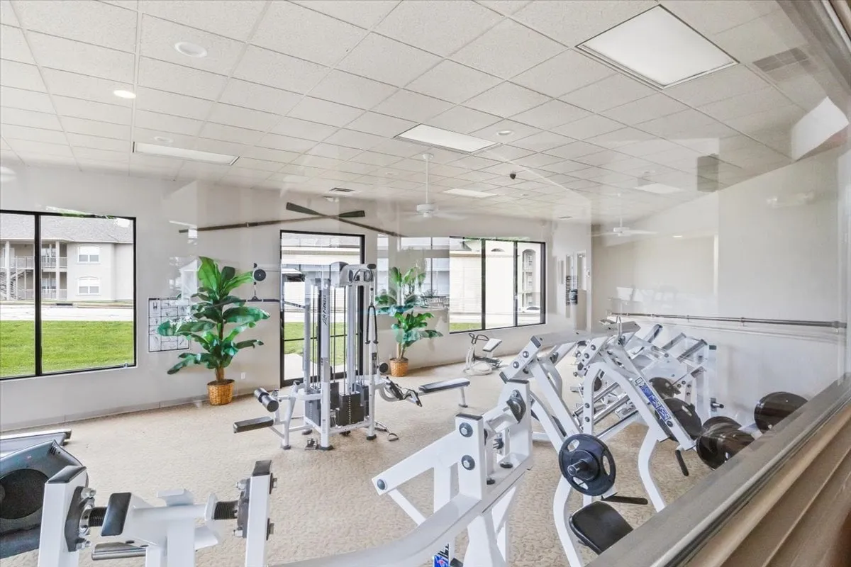 A bright, motivating interior photo of the fitness center featuring modern weight machines, large windows with outdoor views, and uplifting greenery. The space is open, fresh, and welcoming for fitness enthusiasts.